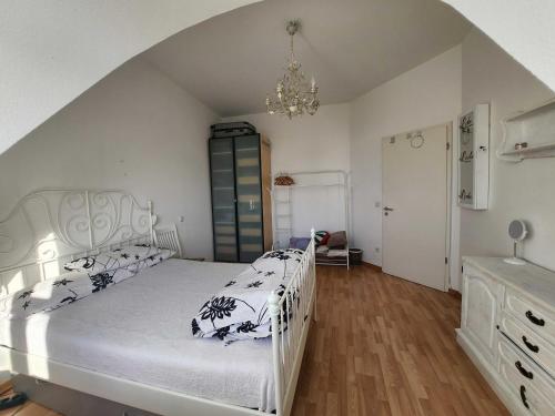 柏林One Private room available in a two room apartment in Tegel, Berlin的卧室配有一张带吊灯的大型白色床。