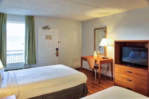威廉斯维尔莫特尔6号布法罗机场汽车旅馆的酒店客房配有一张床、一张书桌和一台电视。