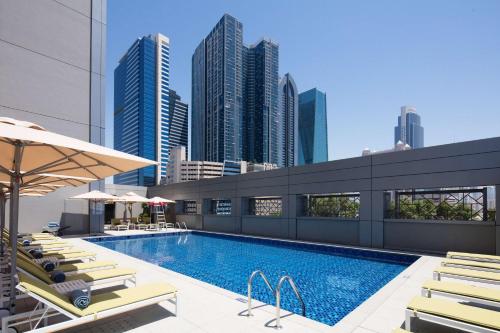迪拜迪拜贸易中心罗弗酒店的一个带躺椅的游泳池,享有城市天际线