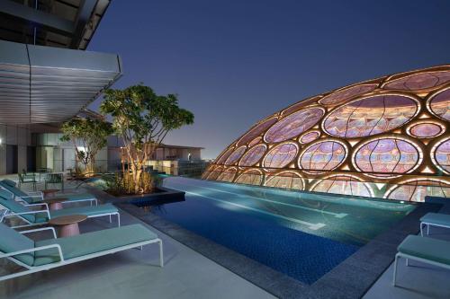 迪拜Rove Expo City的一座带游泳池和椅子的建筑的 ⁇ 染