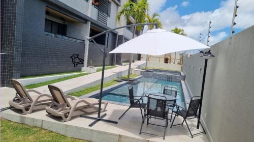 康德Cobertura Vista Mar Carapibus - Cariri Praia - Apartamento completo com 02 quartos的游泳池旁配有桌椅和遮阳伞