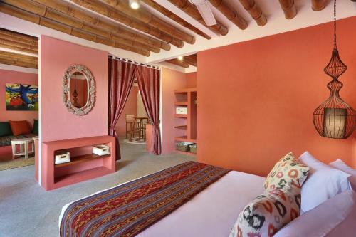 吉利特拉旺安PinkCoco Gili Trawangan - Constant Surprises - for Cool Adults Only的一间卧室设有橙色的墙壁、一张床和镜子