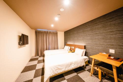 京都HOTEL THE POINT Kiyomizu Gojo的酒店客房设有两张床和一张桌子。