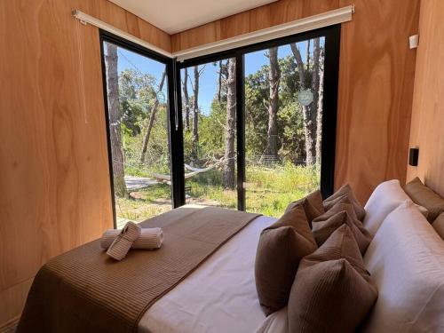 拉佩德雷拉Nandina, en el bosque y playa的一张大床,位于带大窗户的房间里