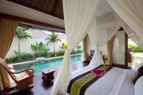 金巴兰Avery Le Nixsun Villas Uluwatu by Waringin Hospitality的一间卧室设有天蓬床和一个游泳池