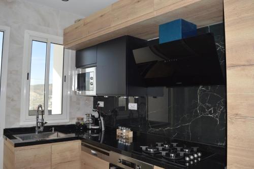 阿加迪尔Appartement 5 etoiles agadir vue mer的厨房配有黑色台面和水槽