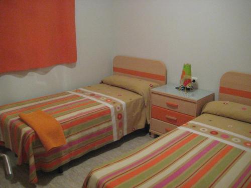 圣卡洛斯拉腊皮塔海岛公寓的一间卧室配有两张床、梳妆台和床套。