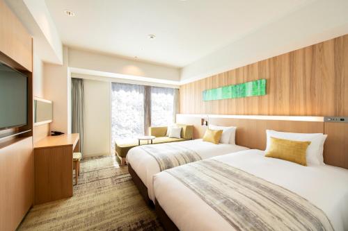 仙台Hotel GrandBach Sendai的酒店客房设有两张床和一台平面电视。