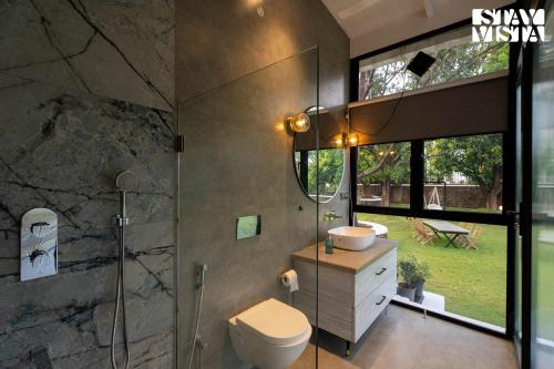 卡尔贾特StayVista's The Oasis - Serene Retreat with Private Pool, Lawn & Gazebo的一间带卫生间和玻璃淋浴间的浴室
