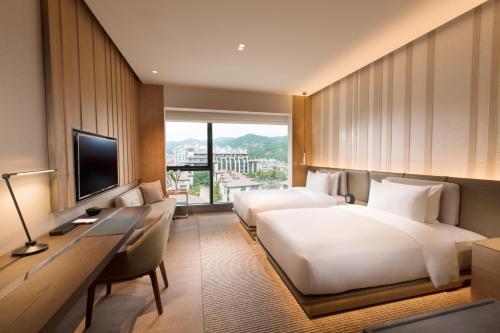 厦门厦门佳逸酒店 希尔顿格芮精选酒店的酒店客房设有两张床、一张桌子和一台电视。