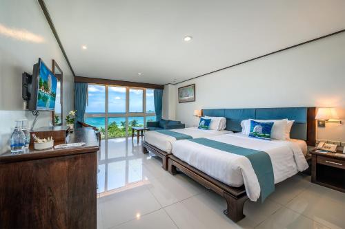 芭东海滩Phuket Karon Emerald Isle Hotel的一间带大床的卧室和一个阳台