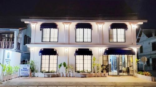 琅勃拉邦Midnight Blue Guesthouse的一座白色的建筑,前面有窗户和植物