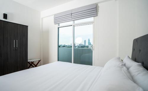 科伦坡Hotel Style Colombo Studio Apartment的卧室设有白色的床和大窗户