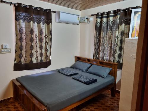 DharmastalaMaison Parnakuti Adigas Homestay Dharmasthala的配有窗帘的小房间中的一张床位
