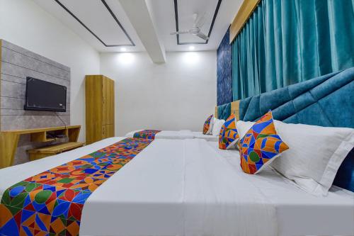 艾哈迈达巴德HOTEL GREEN TREE的卧室配有一张带彩色枕头的大型白色床。