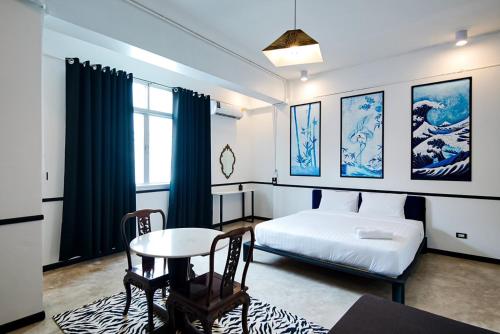 Khlong SanThe Character Yaowarat的卧室配有1张床、1张桌子和1张桌子以及椅子。