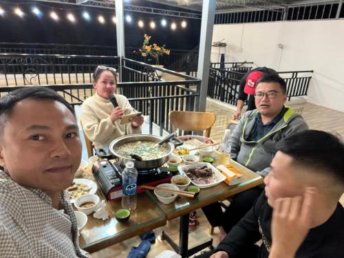 河江Ha Giang Plus Hostel的一群坐在桌子旁吃食物的人