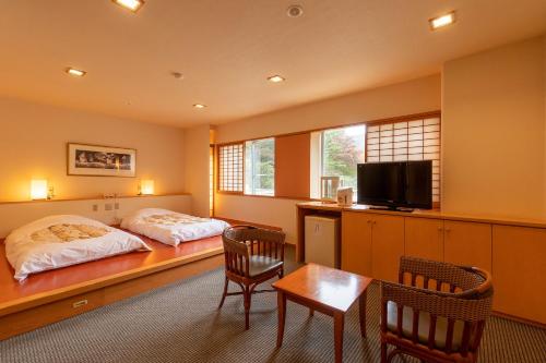 会津若松Ooedo Onsen Monogatari Higashiyama Grand Hotel的一间卧室配有两张床和一张桌子及椅子
