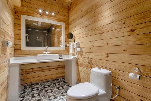 莫尔吉姆Aralea Beach Resort By Stone Wood, Morjim的一间带木墙、卫生间和水槽的浴室