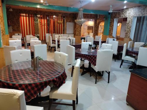 斯利那加Hotel Star of Kashmir的用餐室配有桌子和白色椅子
