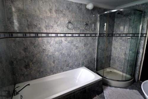 阿尼斯顿Dyers House Kassiesbaai Arniston的带浴缸和玻璃淋浴间的浴室。
