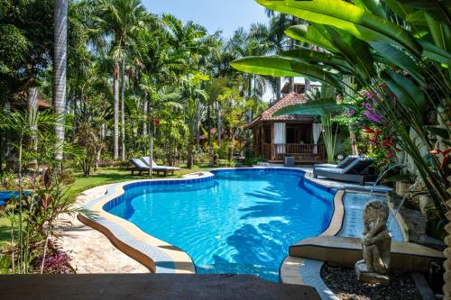 MontongbuwohLombok Stanley Garden Villas的棕榈树和房子的后院的游泳池