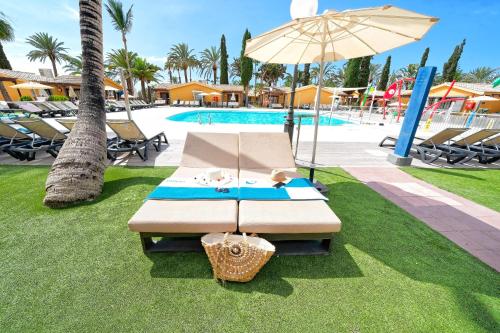 马斯帕洛马斯Suites & Villas by Dunas的游泳池旁带遮阳伞的长凳