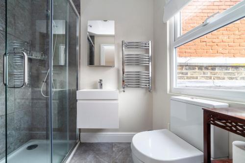 泰晤士河畔金斯顿Stylish 3 BDR apartment wfree parking and garden的带淋浴、卫生间和盥洗盆的浴室