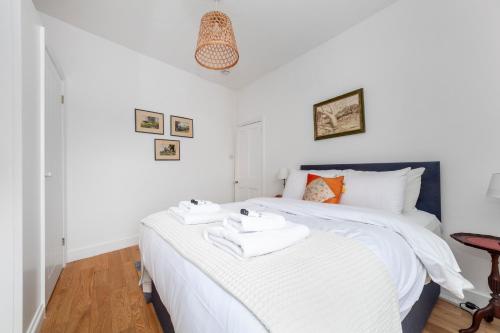 泰晤士河畔金斯顿Stylish 3 BDR apartment wfree parking and garden的卧室配有白色床和毛巾