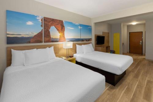 俄克拉何马城俄克拉荷马城戴斯酒店及套房 的酒店客房设有两张床,墙上挂有绘画作品
