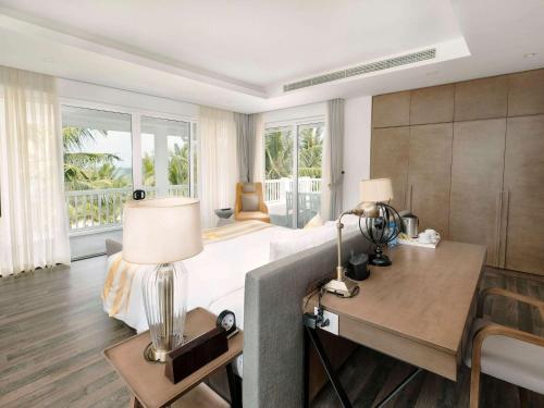 岘港Premier Village Danang Resort Managed By Accor的一间卧室配有一张床和一张带台灯的书桌