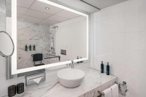 维也纳Hilton Vienna Waterfront的白色的浴室设有大镜子和水槽