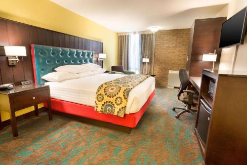 圣安东尼奥圣安东尼奥机场梨树酒店的酒店客房设有一张大床和一张书桌。
