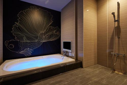 尼崎市ホテル 尼乃美楽 尼崎的带浴缸的浴室和电视。