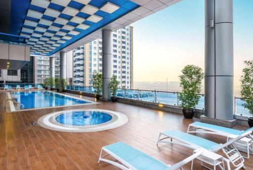 迪拜Ramada by Wyndham Dubai Barsha Heights的一座带椅子的建筑的顶部游泳池