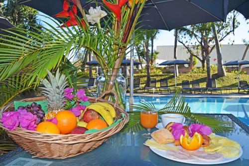 圣吉尔莱班Hotel Exsel Alamanda的两个篮子的水果放在一个游泳池旁的桌子上