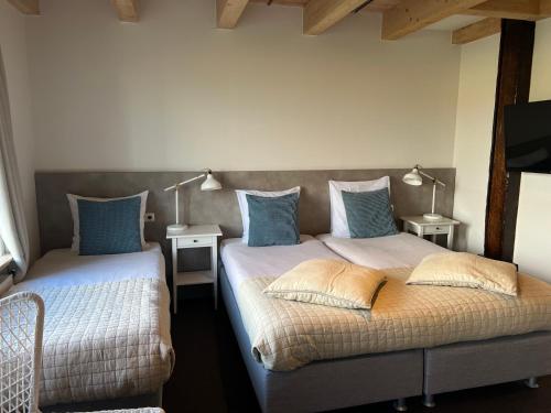 东弗利兰Hotel Posthuys Vlieland的卧室内的两张床,配有蓝色枕头