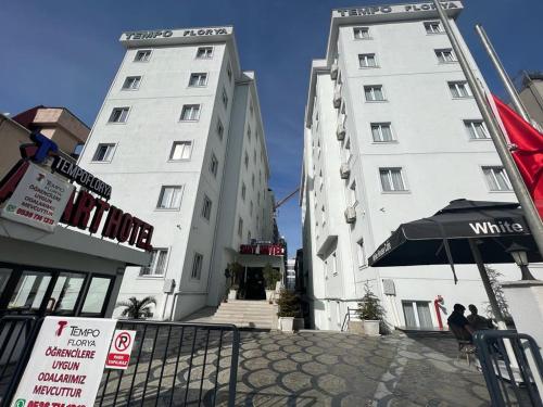 伊斯坦布尔Tempo Florya Otel的两座高大的白色建筑,前面有一把伞