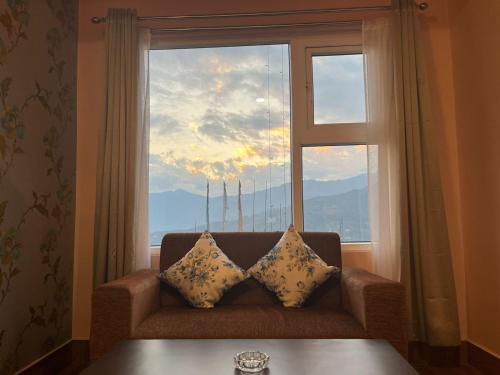 甘托克Little Sikkim Inn的一张沙发,坐在大窗户前