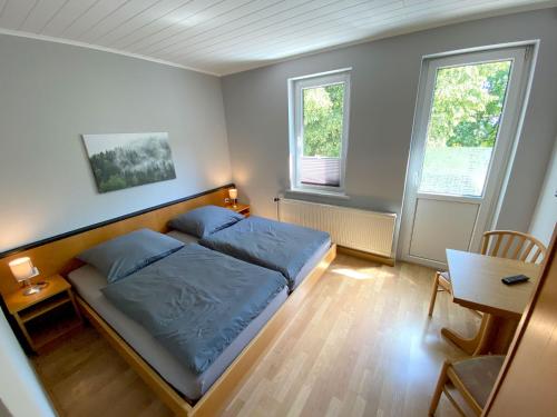 哥达Stadtgarten Gotha的一间卧室配有一张床、一张桌子和两个窗户