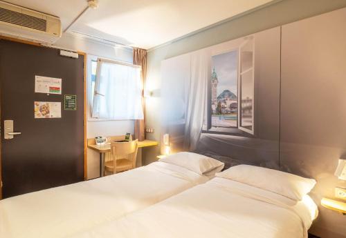 里摩日B&B HOTEL Limoges 2的一间卧室设有两张床、一张桌子和一个窗口