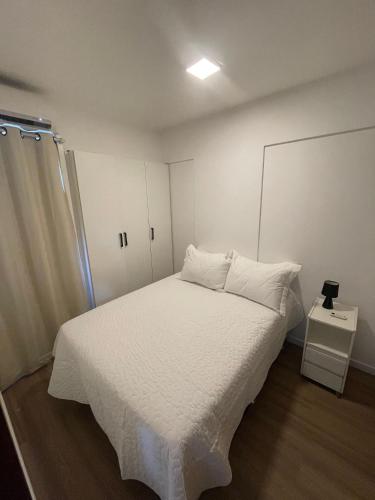 巴西利亚Loft Residencial GreenPark by Staya的一间卧室配有一张带白色床单的床和橱柜。
