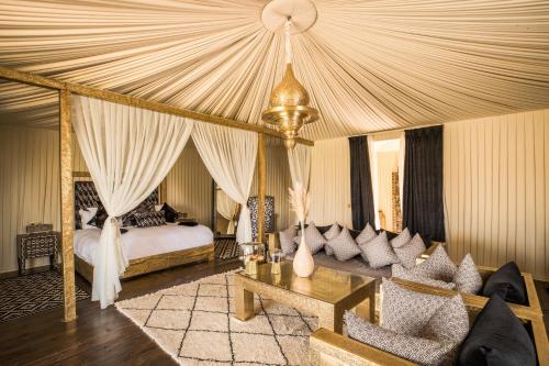 拉拉塔可库斯特Kalyptus Luxury Camp的一间带天蓬床的卧室和一间客厅