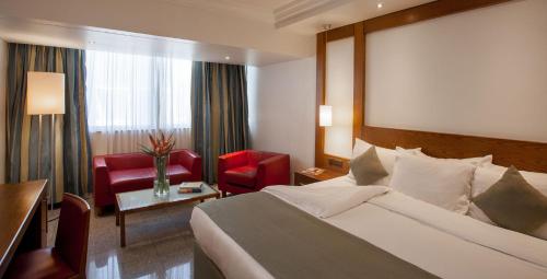 拉各斯Eko Hotel Gardens的酒店客房,配有一张床和一张红色椅子