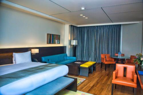 拉各斯Eko Hotel Signature的酒店客房带一张床、一张桌子和椅子