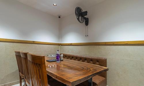班加罗尔Treebo Trend Tiba的一张带椅子的木桌和墙上的时钟