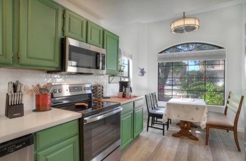 喷泉山Fountain Hills Bungalow West的厨房配有绿色橱柜和桌椅