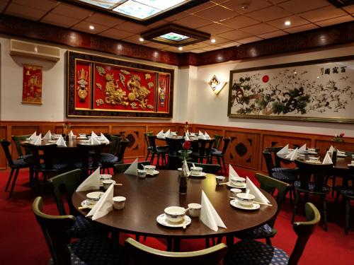罗滕堡China Restaurant Hotel Lotus的用餐室配有桌椅,墙上挂有绘画作品