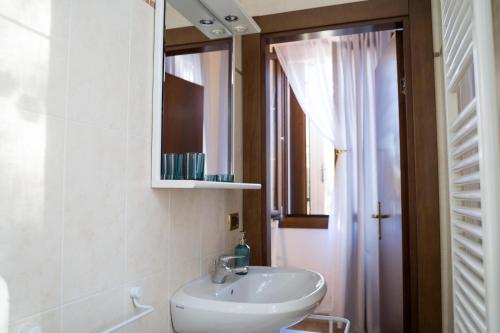 马格拉All’Altana b&b apartment的一间带水槽和镜子的浴室以及窗户。