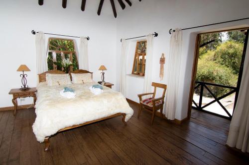 乌鲁班巴阿尔克艾莉丝宾馆的卧室配有一张床和一张桌子及椅子
